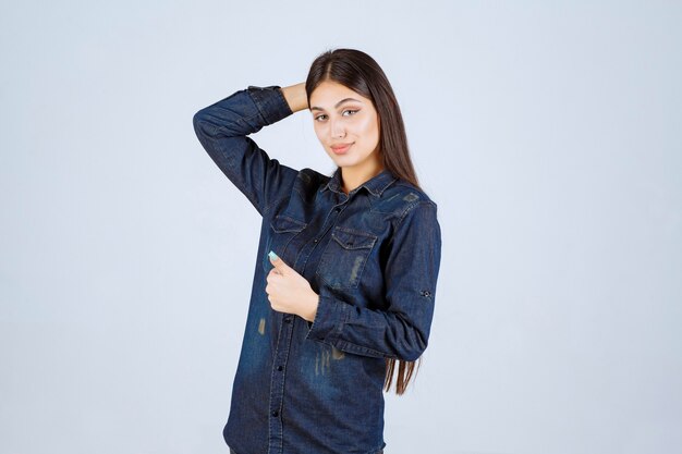 Молодая женщина в джинсовой рубашке показывает положительный знак рукой