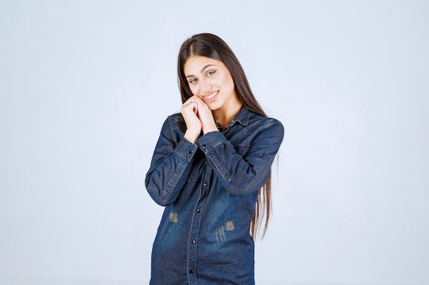 Young woman in denim shirt smiling and making pretty face