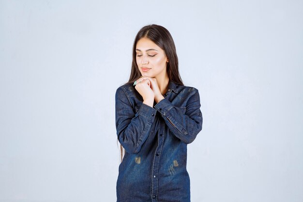 Young woman in denim shirt smiling and making pretty face