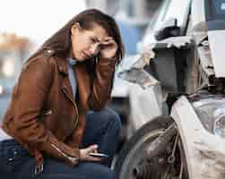 Free photo young woman in despair crying next to her wrecked car