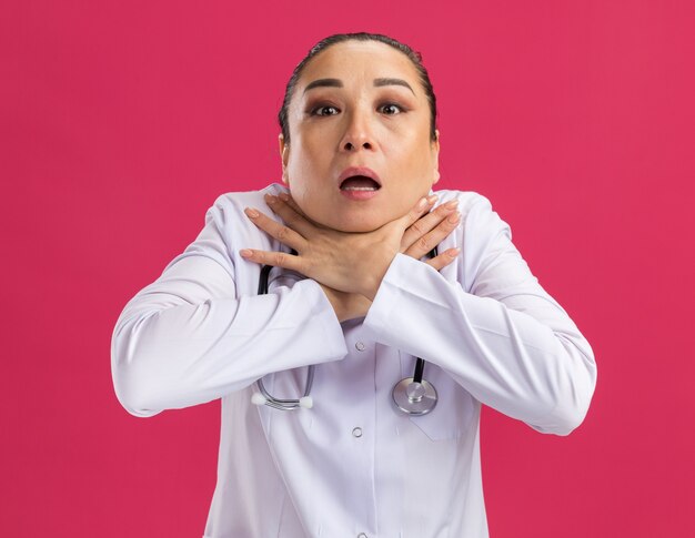 Young woman doctor   choking holding hands on neck in panic