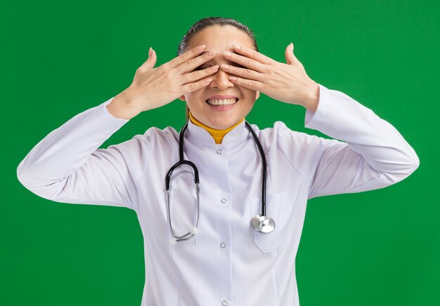 Young woman doctor   covering eyes with hands smiling cheerfully