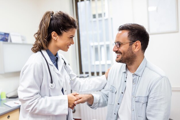 Young woman doctor or GP in white medical uniform consult male patient in private hospital Female therapist speak talk with man client on consultation in clinic