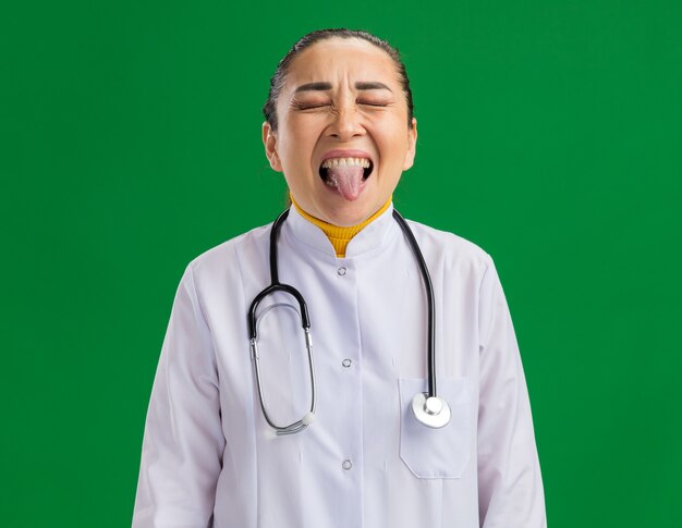 Young woman doctor   happy and joyful sticking out tongue