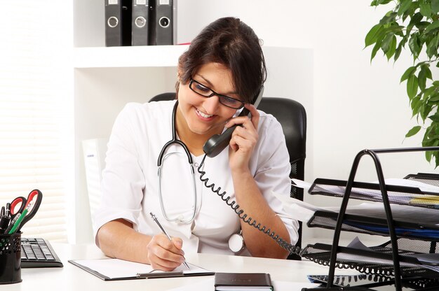 Young woman doctor talking by phone