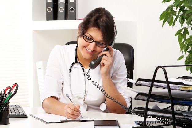 Young woman doctor talking by phone