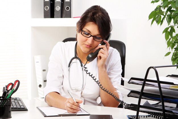 Young woman doctor talking by phone