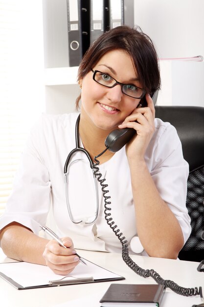 Young woman doctor talking by phone