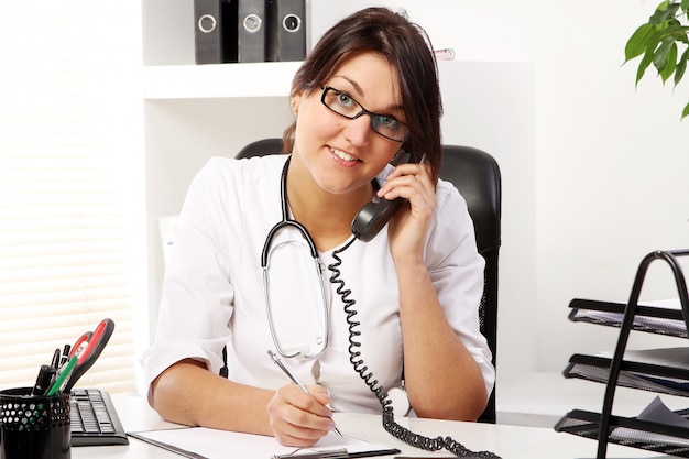 Young woman doctor talking by phone
