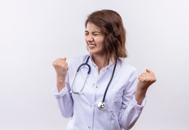 イライラした表情で拳を食いしばって聴診器で白衣を着た若い女医師