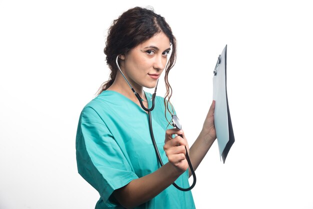 청진 기 흰색 배경에 유니폼에 클립 보드를 들고 젊은 여자 의사. 고품질 사진