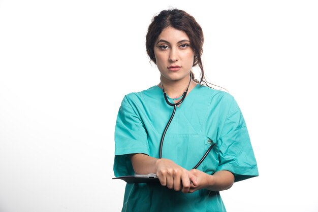 Young woman doctor with stethoscope holding clipboard on white background