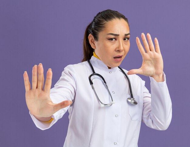 Young woman doctor     worried making defense gesture with hands