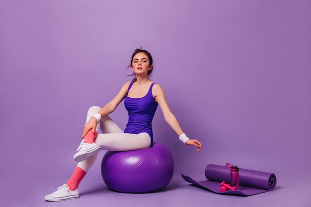 Young woman does aerobics on purple wall