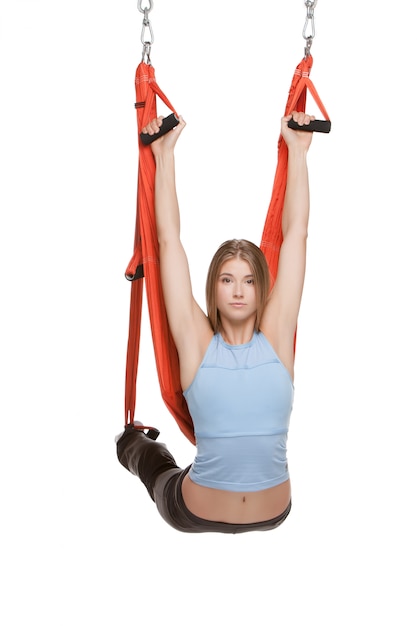 Young woman doing anti-gravity aerial yoga in hammock on a seamless white