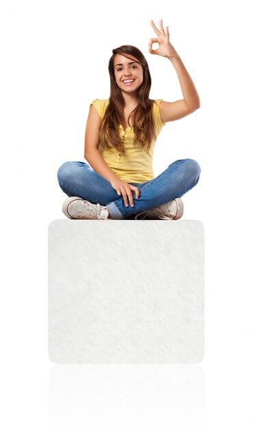 young woman doing approval sign sitting on a banner
