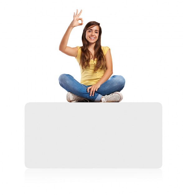 young woman doing approval sign sitting on a banner