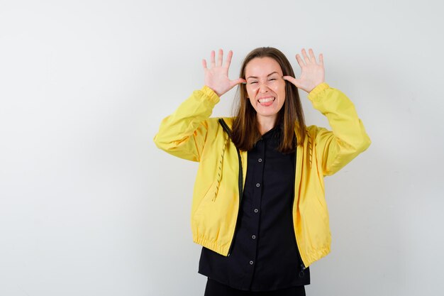 Young woman doing funny gesture and looking happy