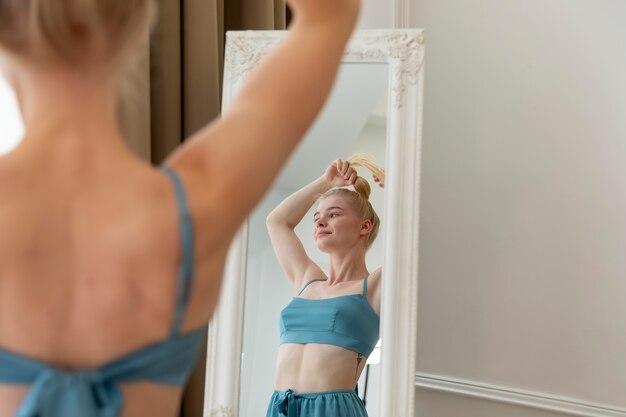 Young woman doing her hair in the mirror