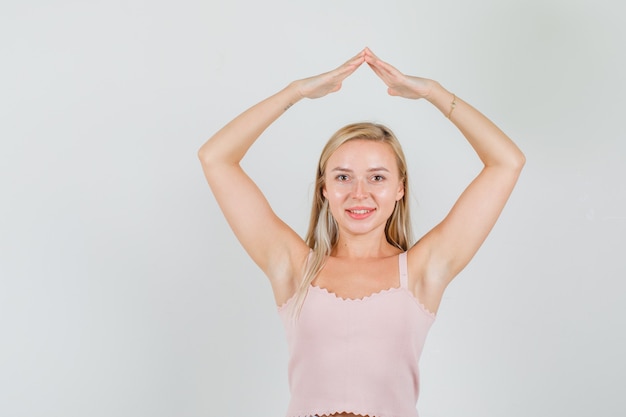 Young woman doing house roof sign over head in singlet