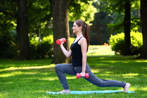 Young woman doing lunges with dumbbells