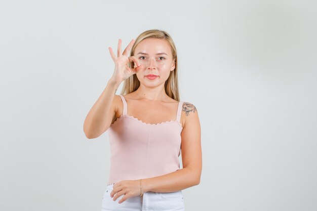 Young woman doing ok sign in singlet