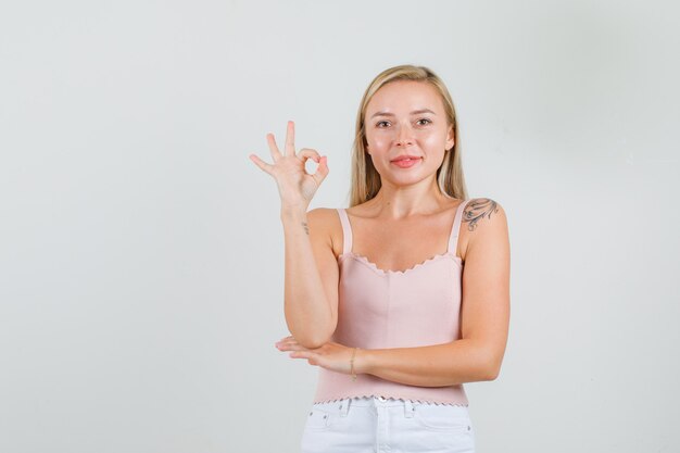 Young woman doing ok sign and smiling in singlet