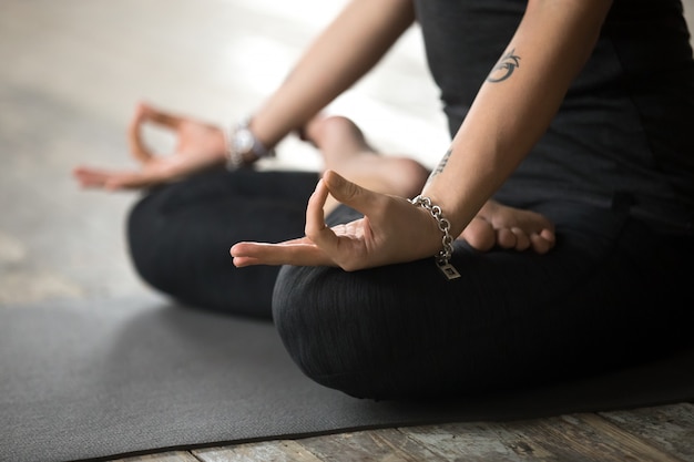 Young woman doing Padmasana exercise, mudra gesture close up