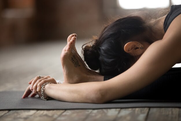 Young woman doing paschimottanasana exercise