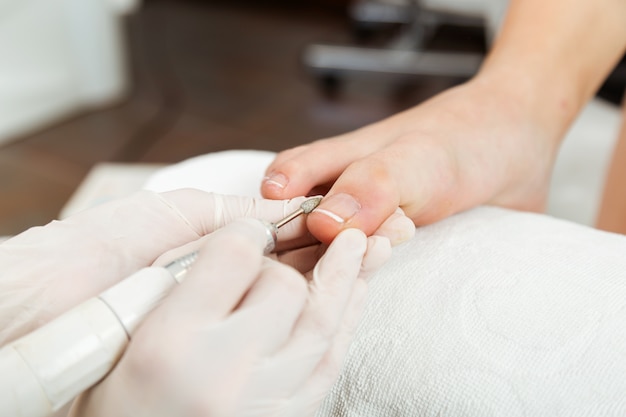 Young woman doing pedicure in salon. Beauty concept.