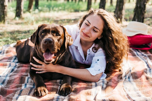 彼女の犬と一緒にピクニックをしている若い女性