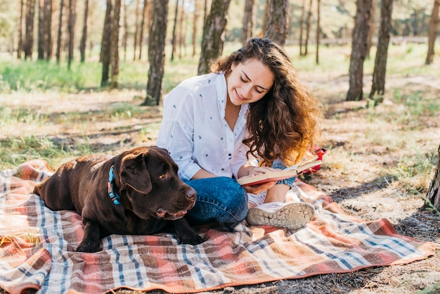 彼女の犬と一緒にピクニックをしている若い女性