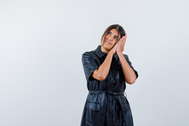 Young woman doing a sleep hand gesture on white background