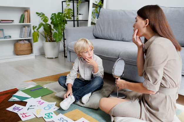 Young woman doing speech therapy with a little blonde boy