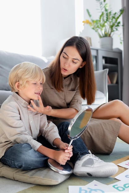 Young woman doing speech therapy with a little blonde boy