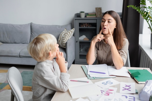 Free photo young woman doing speech therapy with a little boy