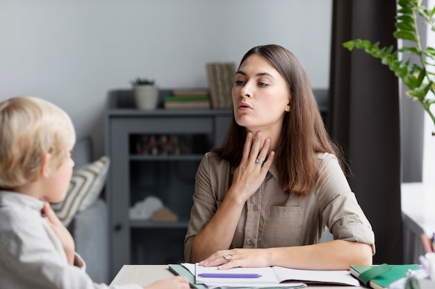 Young woman doing speech therapy with a little boy