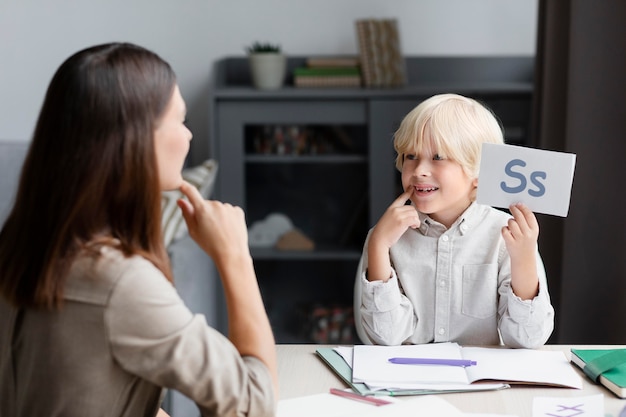 Free photo young woman doing speech therapy with a little boy