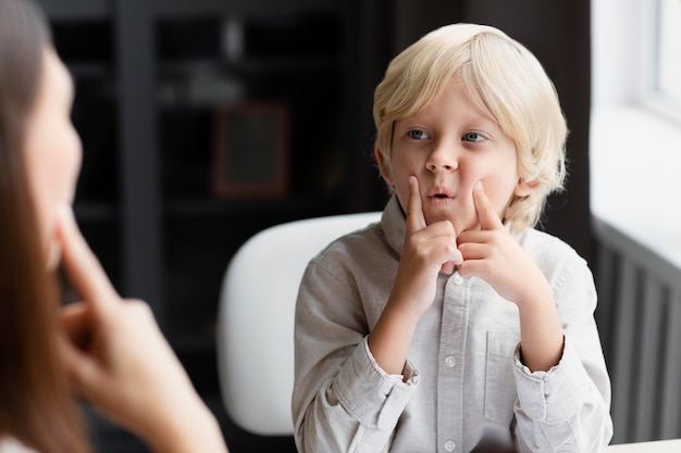 Free photo young woman doing speech therapy with a little boy