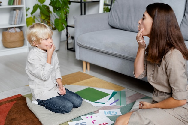 Young woman doing speech therapy with a little boy