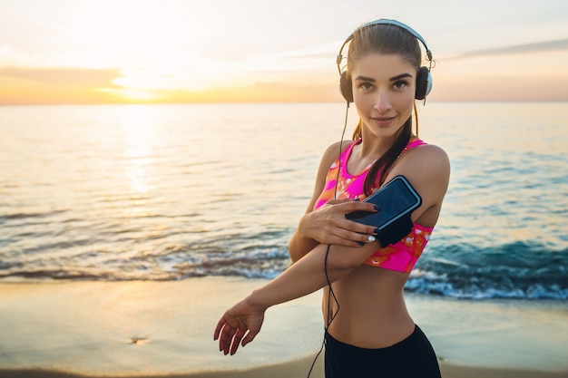 Young woman doing sport exercises on sunrise beach in morning