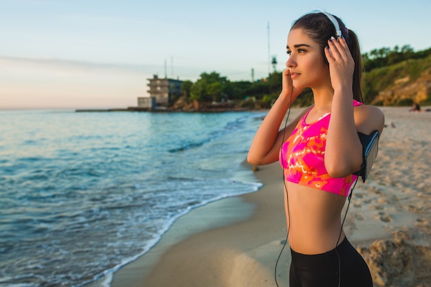 Young woman doing sport exercises on sunrise beach in morning