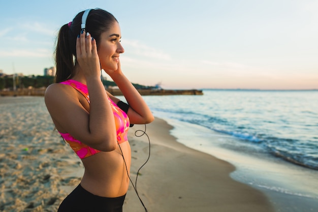 Young woman doing sport exercises on sunrise beach in morning