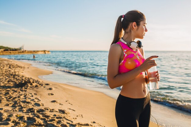 Young woman doing sport exercises on sunrise beach in morning