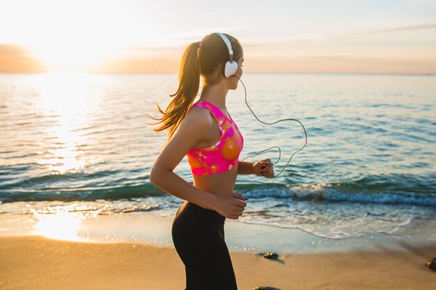 Young woman doing sport exercises on sunrise beach in morning