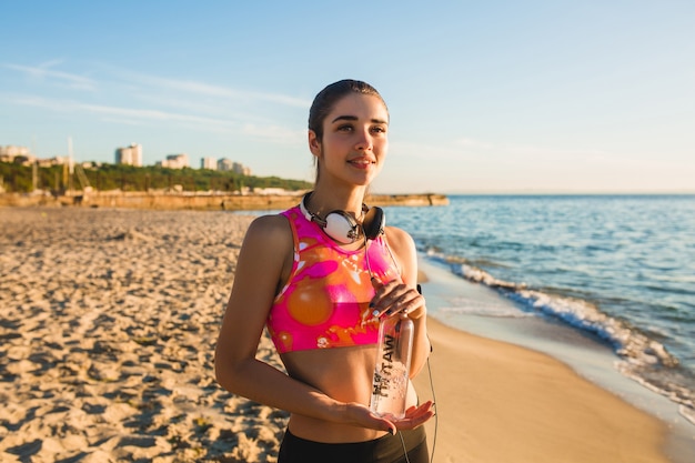 Молодая женщина делает спортивные упражнения на пляже восхода солнца утром