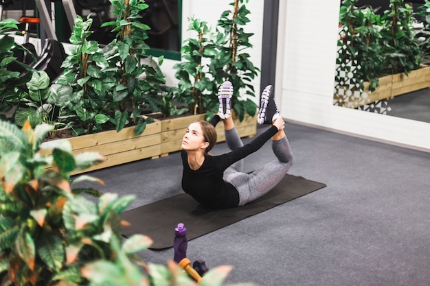 Молодая женщина делает растяжения упражнения на йога коврик