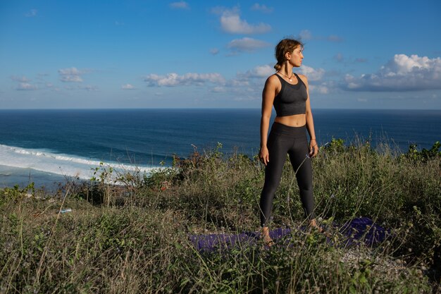 Young woman doing yoga outdoors with amazing back view. Bali. Indonesia.