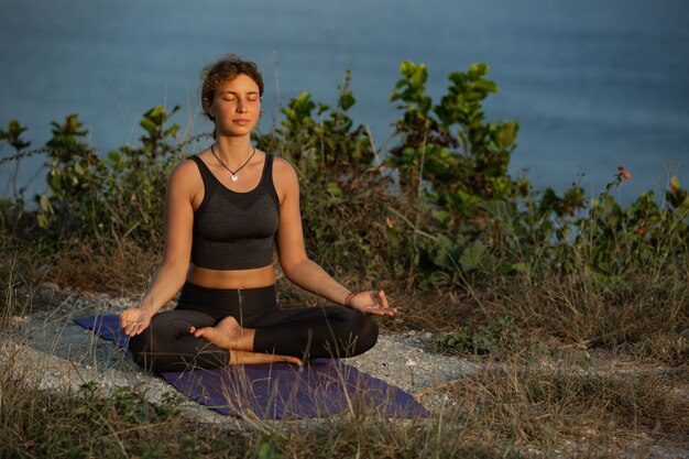 Young woman doing yoga outdoors with amazing back view. Bali. Indonesia.