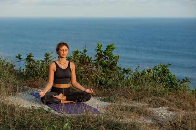 Young woman doing yoga outdoors with amazing back view. Bali. Indonesia.